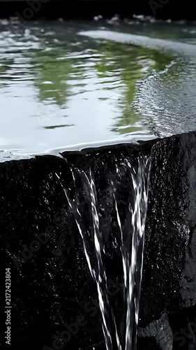 Gentle water cascades over dark textured rocks in a serene natural setting