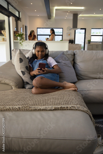Quadro su tela Diverse female family youth sitting at home wearing headset holding red phone wh