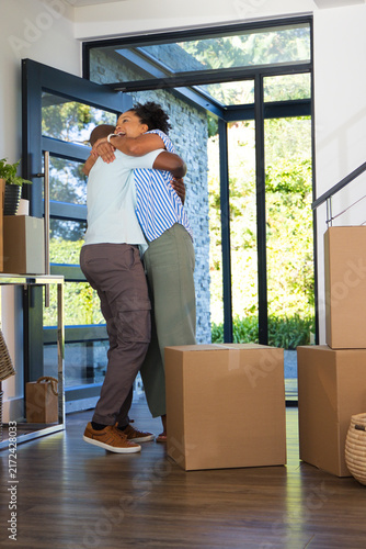 фотографія African American couple hugging in foyer at open glass front door with sealed mo
