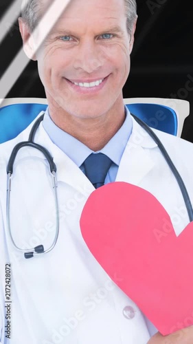 Animation of financial graphs, data and globe over happy caucasian doctor holding heart