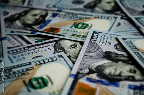 Background of scattered one hundred US dollar bills featuring Benjamin Franklin portrait, representing wealth, banking, finance, investment, currency exchange, and economy. Paper money concept