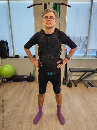 Foto Man stands in gym wearing fitness vest and purple socks electro muscle stimulati