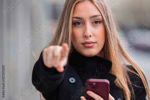 Принти на полотні young woman pointing at camera with mobile phone