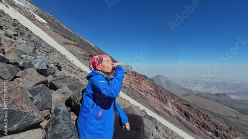 Female tourist drinks water in side view on Mount Ararat during an acclimatization hike, highlighting high altitude hydration, mountain trekking, expedition training, endurance, and adventure travel