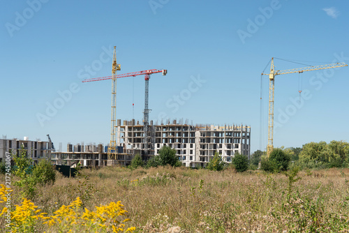 Construction of a high-rise residential complex with tower cranes. Real estate development concept.
