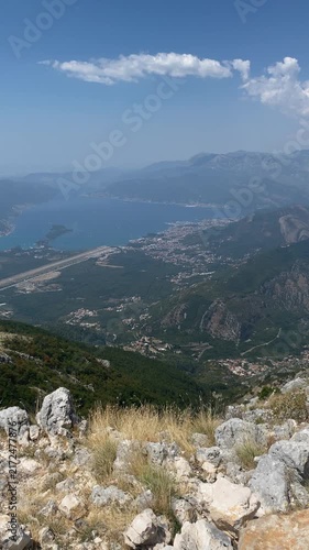 Scenic wide-angle view overlooking the Bay of Kotor and Tivat Airport runway from a high rocky mountain peak in Montenegro