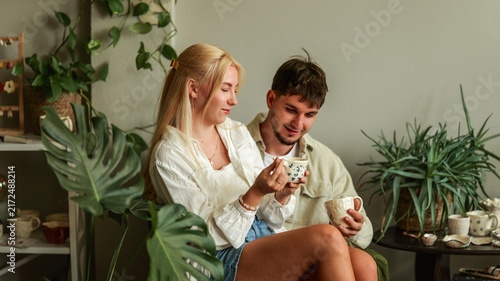 Bild auf Leinwand Young couple enjoying coffee together surrounded by lush indoor plants