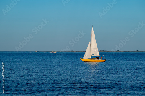 Cuadro en lienzo White sailboat crossing calm blue water beneath a clear sky