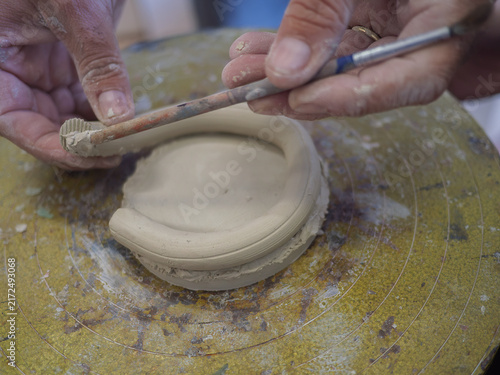 Obraz na plátně An artisan carefully pressing and shaping a circular raw clay base on a studio table focusing on traditional handbuilding techniques and the fundamental process of authentic ceramic craftwork