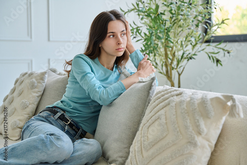 Canvastavla Pensive teen student girl sitting thoughtful on sofa leaning hand