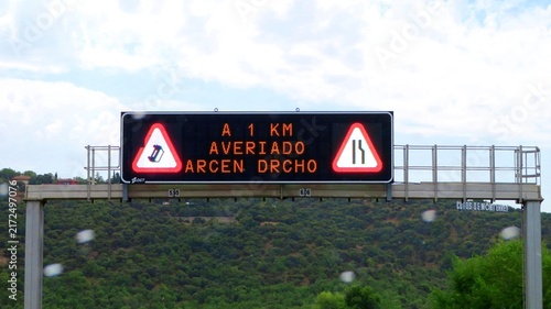 Fotografie An electronic road information sign above the A-1 motorway in Spain, warning drivers of a broken-down car 1 km away and advising them to take care when crossing