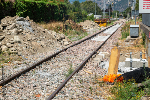 Railroad tracks, tunnel entrance, train, nature, mountain landscape, vegetation, metal structures, pylons, stone, railway construction site, transportation, summer, day, perspective, path, track