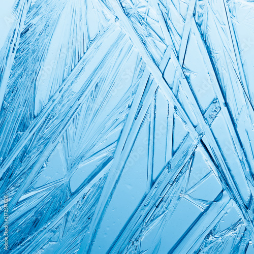 Ice frozen in intricate patterns of delicate crystals in blue and teal. Detai...