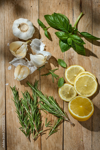 Fresh Garlic, Basil, Rosemary and Lemon on Rustic Wooden Table, Top View