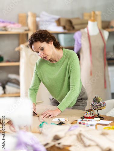 Fotografía Female tailor cutting paper with scissors, cutting out the outline of a pattern