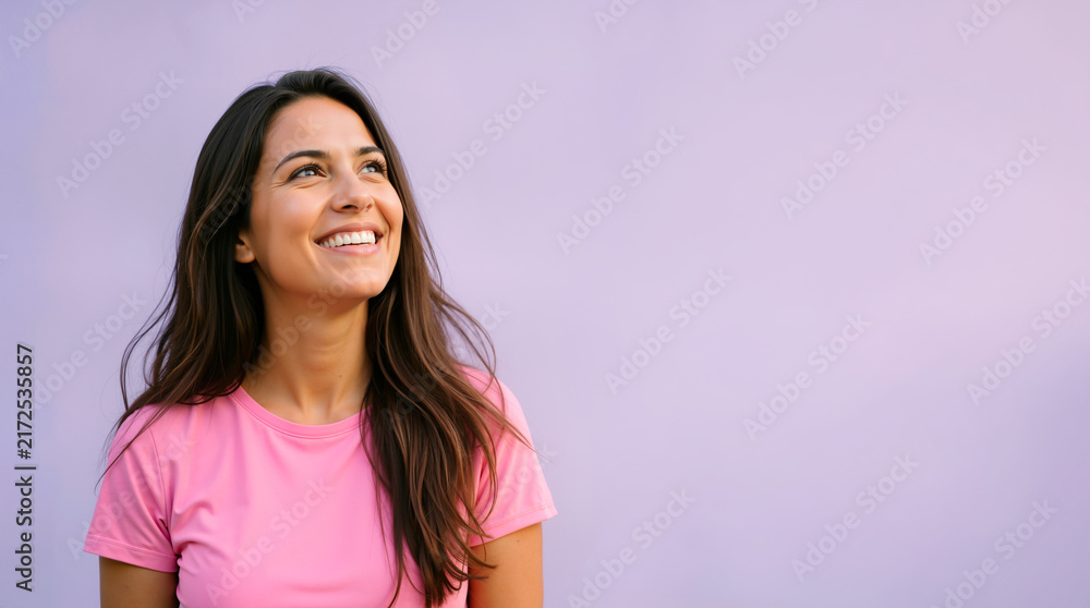 Fototapeta premium Smiling young woman looking up with a happy expression. Cheerful female portrait against a solid purple background. Copy space for text