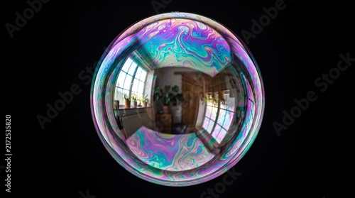 Close-up of a soap bubble refracting rainbow colors and city reflections on a dark background.