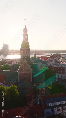 Aerial view showing the historic Riga Cathedral and Old Town architecture with the Daugava river bathed in warm sunset light in Latvia.