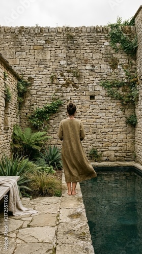 Back view of woman looking at serene stone pool in courtyard setting