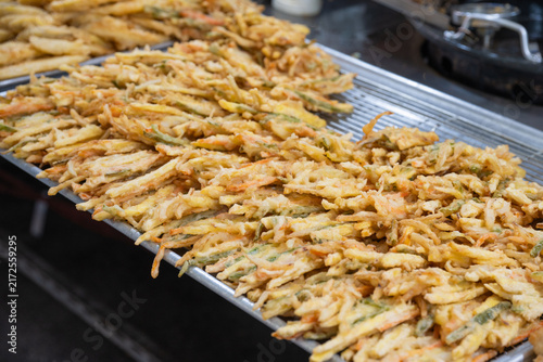 Obraz na plátně Close up view of freshly cooked crispy mixed vegetable fritters stacked at a traditional market food stall