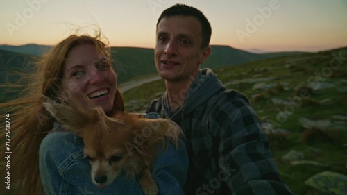 Couple enjoys time in mountains with their dog during sunset in the evening