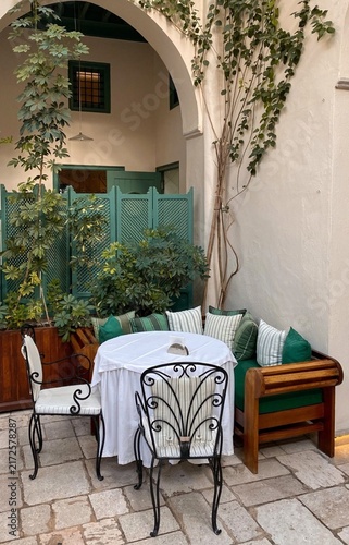 outdoor patio with flowers
Cozy outdoor patio seating area in a rustic Mediterranean courtyard a round table with a white tablecloth, wrought-iron chairs. Fondouk El Attarine,  
Tunisia, mednia tunis.