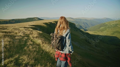 Woman hiking on a path in the mountains during the day with clear skies and hills in the background