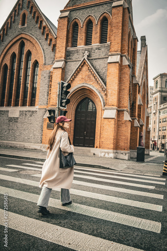 Photography Woman crossing street back view near Union Church, Shanghai