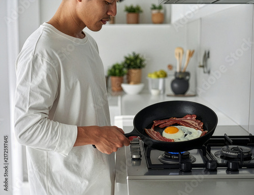 目玉焼きを作る若い男性