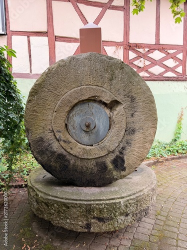 Alter Mühlstein an einem Fachwerkhaus.
