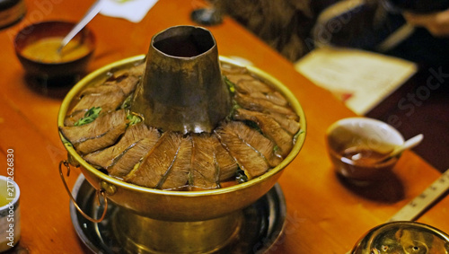 Картината върху платно Shangri-La,China - February 18, 2012: A traditional Tibetan style copper hotpot loaded with sliced yak meat and greens