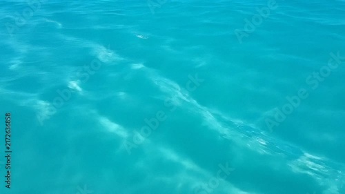 crystal clear turquoise ocean water surface, sunlight dappling the depths, serene tropical seascape, perfect for vacation branding or calm background visuals
