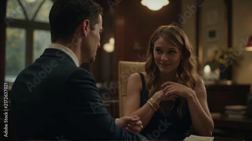 Elegant Woman in Dark Dress Smiles While Talking to Man in Suit in Office