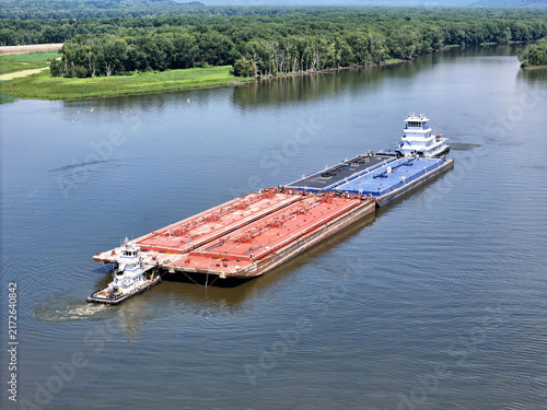 Set of liquid cargo barges being guided by a small service tug