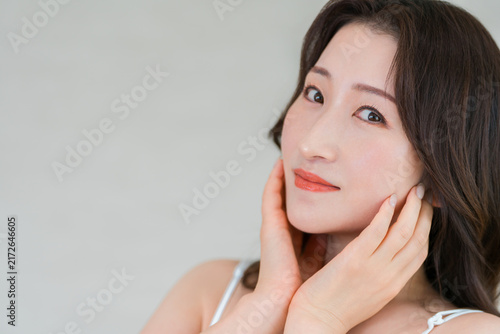 фотографія A middle-aged Asian woman with her hand on her cheek, skincare image