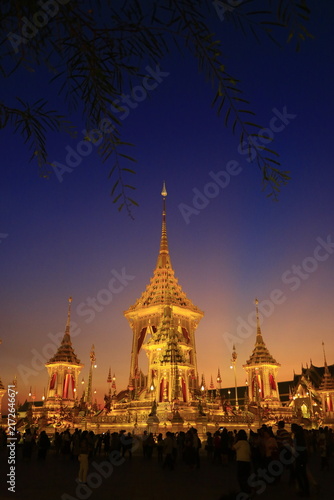Bild auf Leinwand Phra Merumat at twilight with visitors and tree branches framing the golden stru