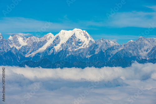 Panoramic views of snow-covered mountain peaks rising above a spectacular sea of clouds under clear blue skies, seen from Niubei Mountain in Sichuan, China