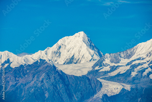 Panoramic views of snow-covered mountain peaks rising above a spectacular sea of clouds under clear blue skies, seen from Niubei Mountain in Sichuan, China