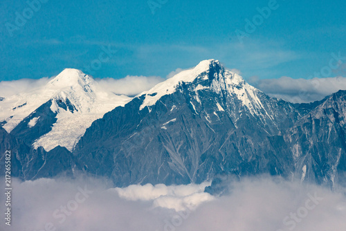 Panoramic views of snow-covered mountain peaks rising above a spectacular sea of clouds under clear blue skies, seen from Niubei Mountain in Sichuan, China