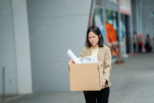Fotografía A businessman who has lost his job walks out of the office carrying a box of his belongings, feeling sad and frustrated