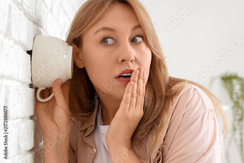 Bild auf Leinwand Gossip and eavesdropping concept, curious woman listening through a wall with a