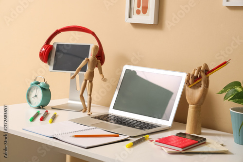 Inventors workplace with blank laptop and tablet computer near beige wall in office