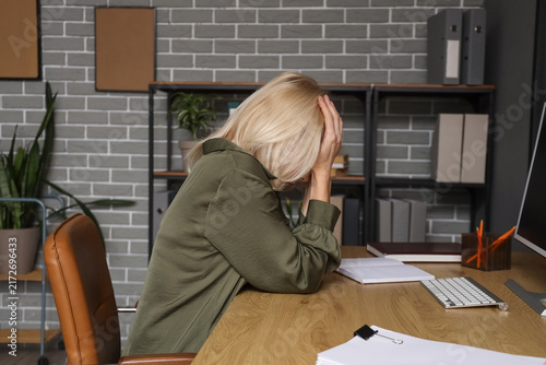Worried mature businesswoman at table in office