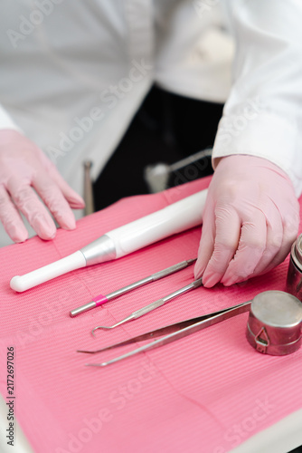 Cuadro en lienzo Dentist wearing pink gloves placing various instruments on a pink medical tray f