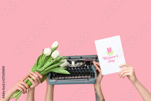 Hands holding vintage typewriter, tulips and festive postcard with text HAPPY...