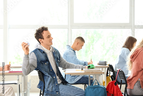 Male student throwing crumpled paper in his classmates at classroom