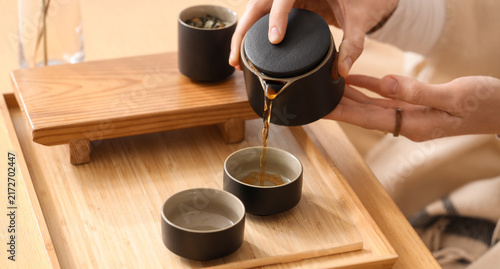 Photography Tea ceremony and mindfulness, woman pouring hot tea into small cups on a wooden