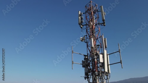 Aerial Footage of Several Radio Masts and Antennas Mounted on a Large Telecommunication Tower During Morning Against a Clear Blue Sky in Karanglewas, Indonesia. 