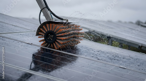 Industrial solar panel cleaning service using a rotating brush and water spray on photovoltaic modules at a renewable energy farm, highlighting professional maintenance for optimal solar cell .