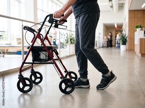 Elderly person using a walker for mobility assistance indoors.